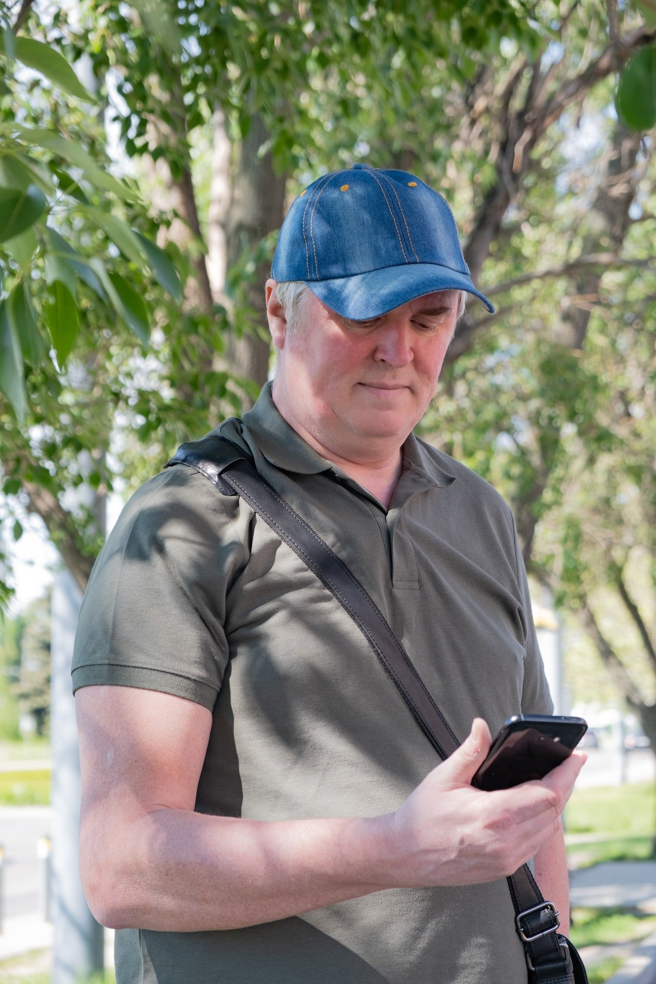middle-aged man in a denim cap with a phone
